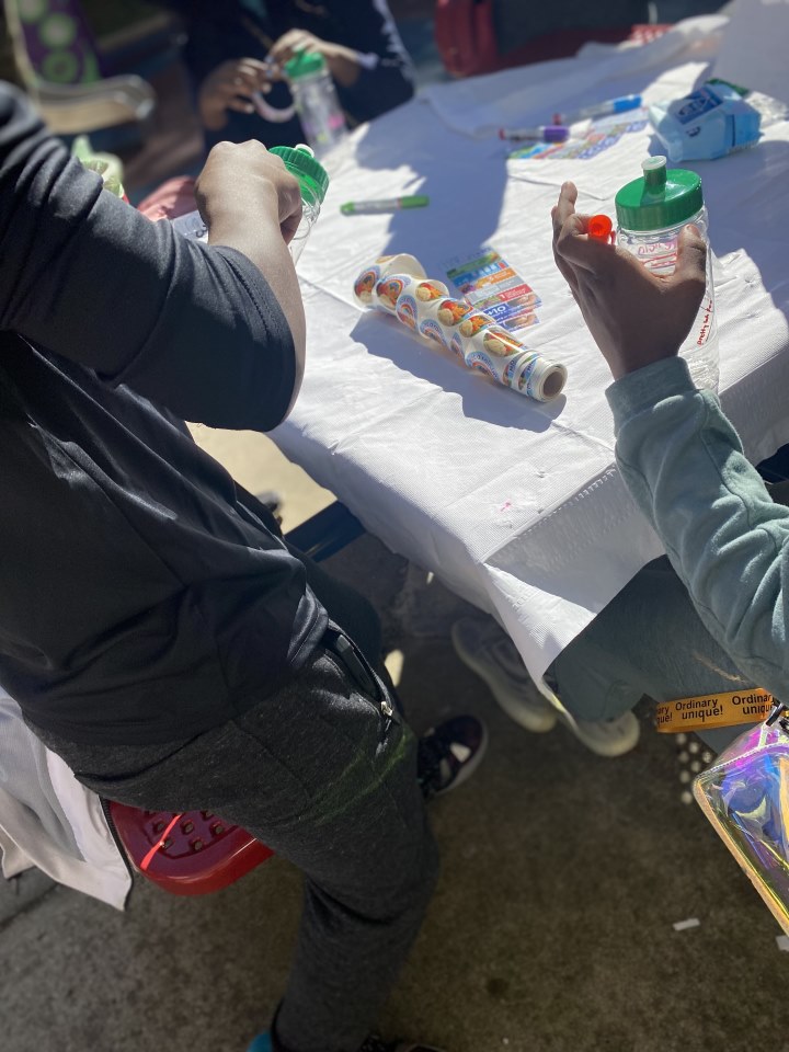 Two youth decorating water bottles at an outdoor event.